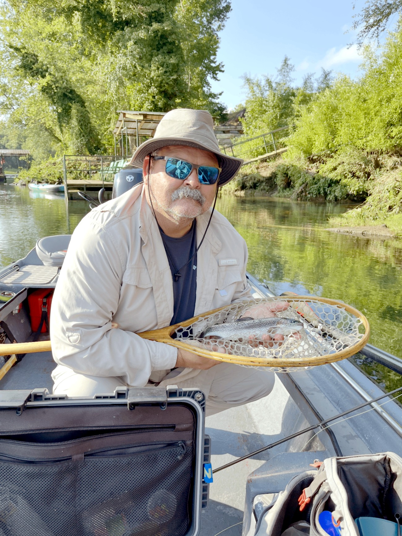Evan Hightower in a boat holding a landing net with a trout.